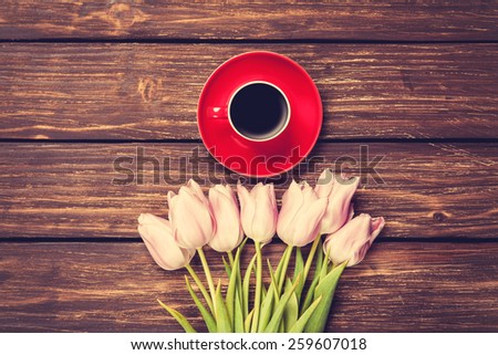 Cup of coffee and bouquet of tulips on a wooden background
