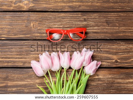 Red glasses and bouquet of tulips on a wooden background