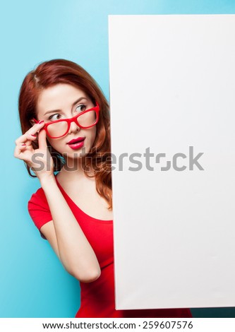 Surprised student girl in red dress and glasses with white board on blue background