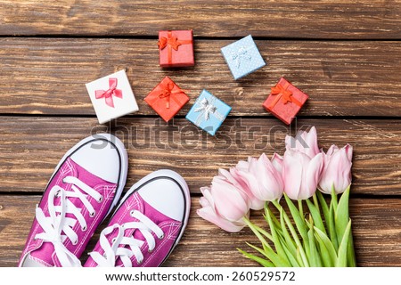 Gym shoes and gift box with tulips on a wooden background