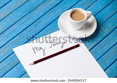 pencil and paper with My Story words near cup of coffee on blue wooden table