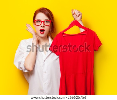 Young redhead designer with red dress on yellow background