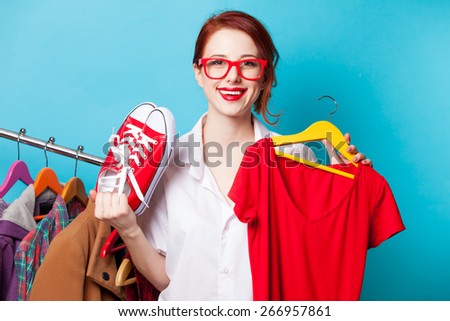 Young redhead designer with red dress and gumshoes on blue background
