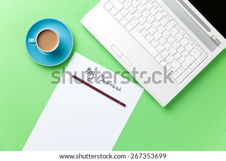 cup of coffee and computer with paper on green background