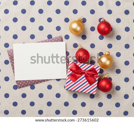 Gift box and envelope with christmas baubles on polka dot background
