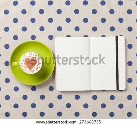 Cup of coffee and notebook on polka dot background.
