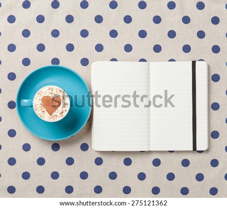 Cup of coffee and notebook on polka dot background.