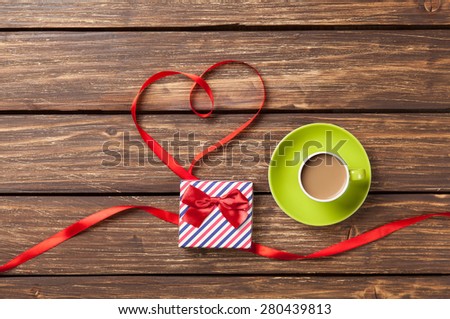 Cup of coffee and bow in heart shape symbol on wooden table