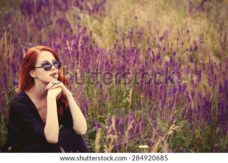 Portrait of a beautiful redhead girl with sunglasses on lavender field.