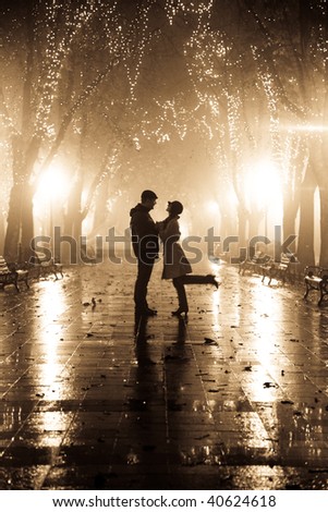 Couple walking at alley in night lights. Photo in vintage yellow style.