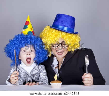 Mother and child in funny wigs and cake at birthday. Studio shot.