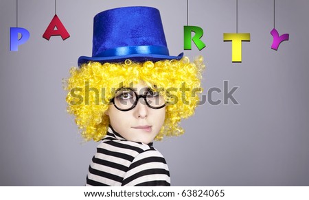 Portrait of yellow-haired girl in blue cap and striped knitted jacket with PARTY lettering. Studio shot.