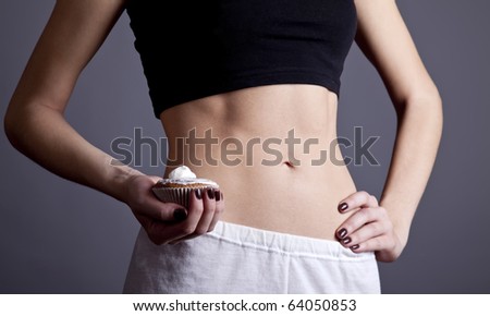 Beautiful and strong women\'s abs with cake. Studio shot.