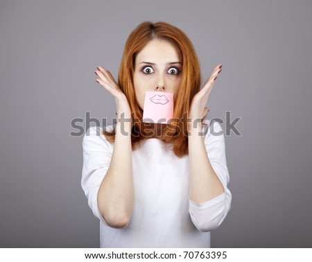 Portrait of red-haired girl with colorful funny stickers on mouth. Studio shot.