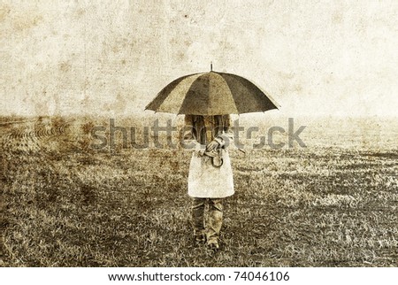 Girl with umbrella staying on field. Photo in old image style.