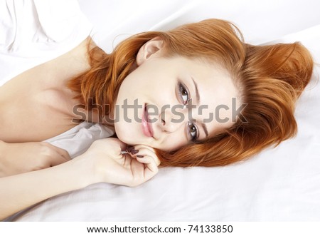 Pretty red-haired sleeping woman in white nightie lying in the bed