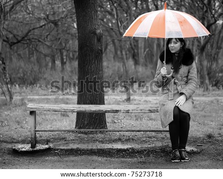 Alone girl sitting at bench in rainy day. Photo in black style.
