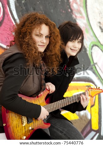 Two style teen girls with guitar at graffiti background.
