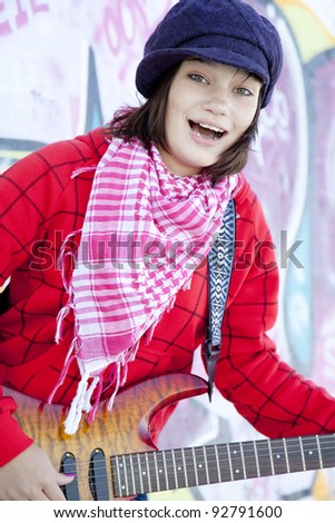 Closeup portrait of a happy young girl with guitar and graffiti on background