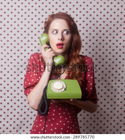 Portrait of a redhead girl with green dial phone on Polka dot background.