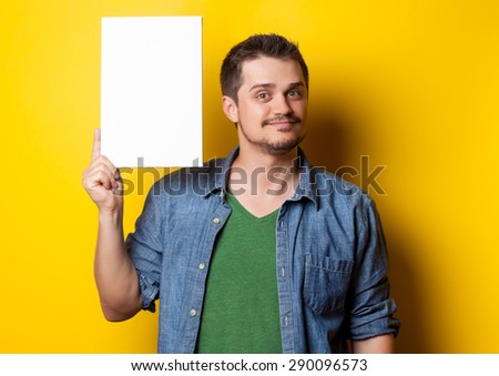 young smiling guy in shirt with white board on yellow background.