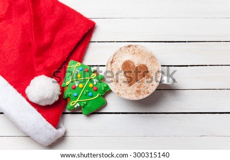 Cup of coffee with heart shape and christmas gingerbread on white wooden background.