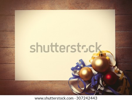 White paper and christmas toys with confetti on wooden background. Photo in old color image style.