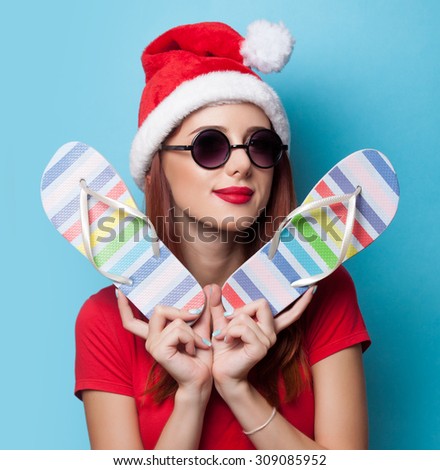 women in christmas hat with flip flops on blue background.