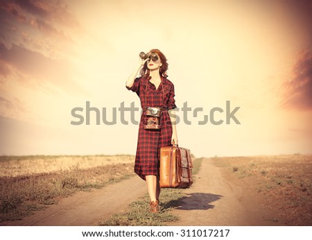 Beautiful girl in plaid dress with bag and binocular on countryside
