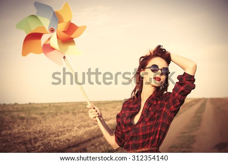 Beautiful girl in plaid dress with wind toy on countryside