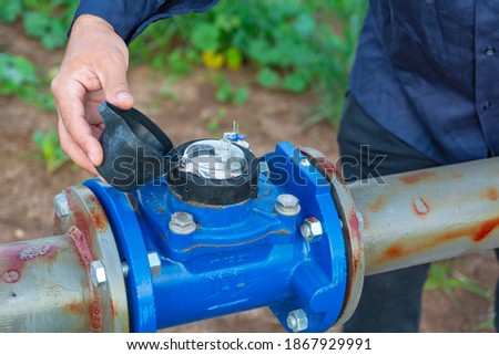 A technician checks a water meter in a water supply system installed in a field. Close-up . Imagine de stoc © 