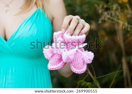 Pregnant woman in casuals with two kinds of socks future baby - white background