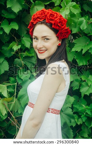 Ukrainian girl in a shirt and a wreath of flowers and ribbons on his head on a background of green grass
