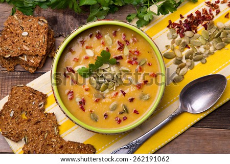 Cream soup from baked butternut squash with thyme and paprika decorated with parsley and with rye crackers with pumpkin seeds and pepper