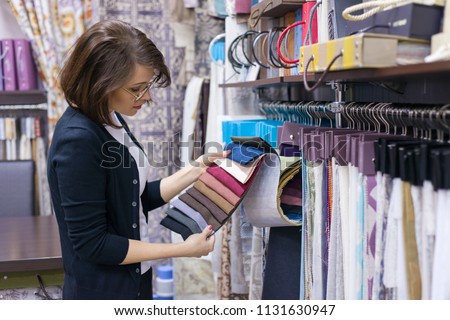 Woman designer, decorator chooses fabrics for curtains, pillows, embroidering fabrics, carpets in the textile show room Stock fotó © 