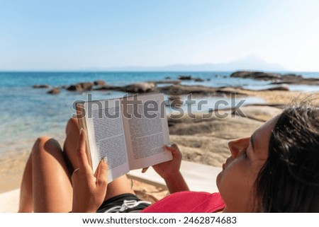 Similar – Image, Stock Photo Reading girl deeply absorbed in a book, stretching her feet from a colorful striped hammock