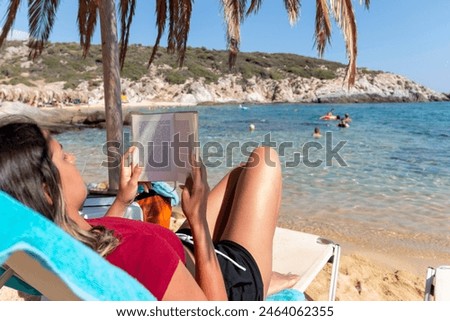 Similar – Image, Stock Photo Reading girl deeply absorbed in a book, stretching her feet from a colorful striped hammock