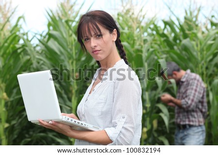 Farming couple with a laptop in a field of corn