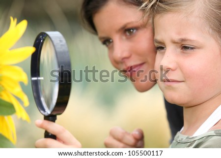 Girl with magnifying glass watching flower