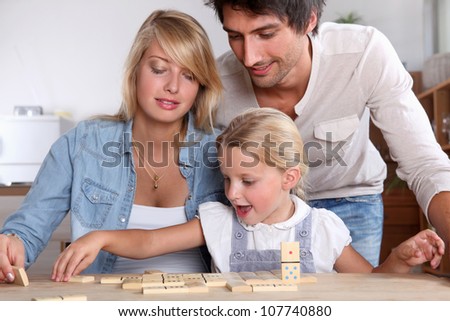 happy couple playing dominos with daughter