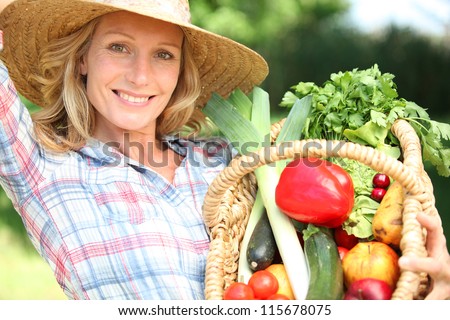 Woman with a straw hat holding basket of vegetables.