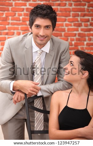 Man in suit sitting behind a woman