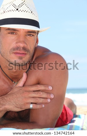 Close up of a man in a straw hat lying on the beach