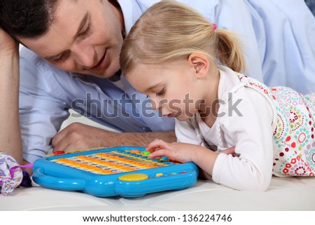 Man playing a toy computer with a little girl