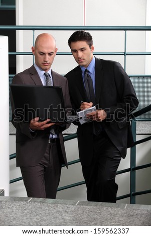 Businessmen comparing notes in stairwell