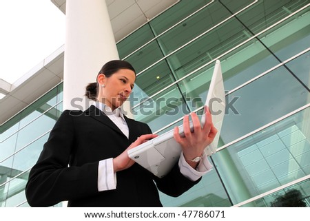 Businesswoman with laptop computer outside a building