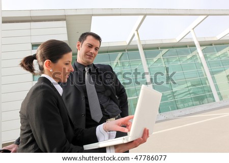 Business people in front of modern building with laptop
