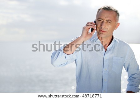 Man talking on mobile phone by the sea