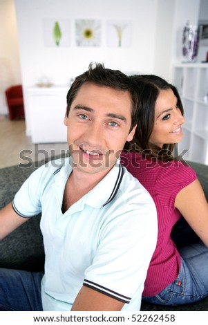 Portrait of a man and a woman sat on a sofa back to back