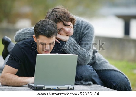 Woman next to a man lying in front of a laptop computer